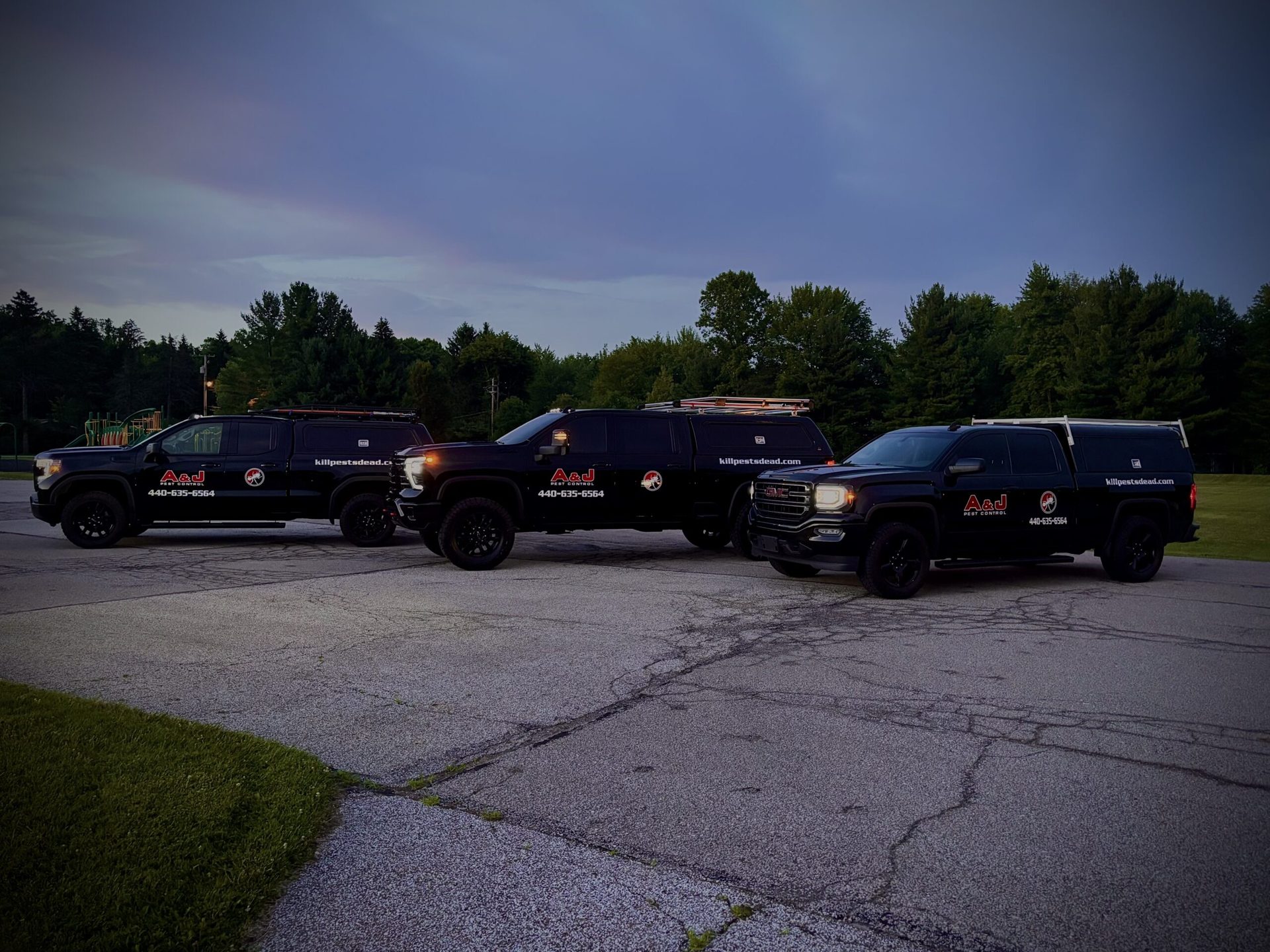 A&J Pest Control service trucks lined up at dusk in Northeast Ohio